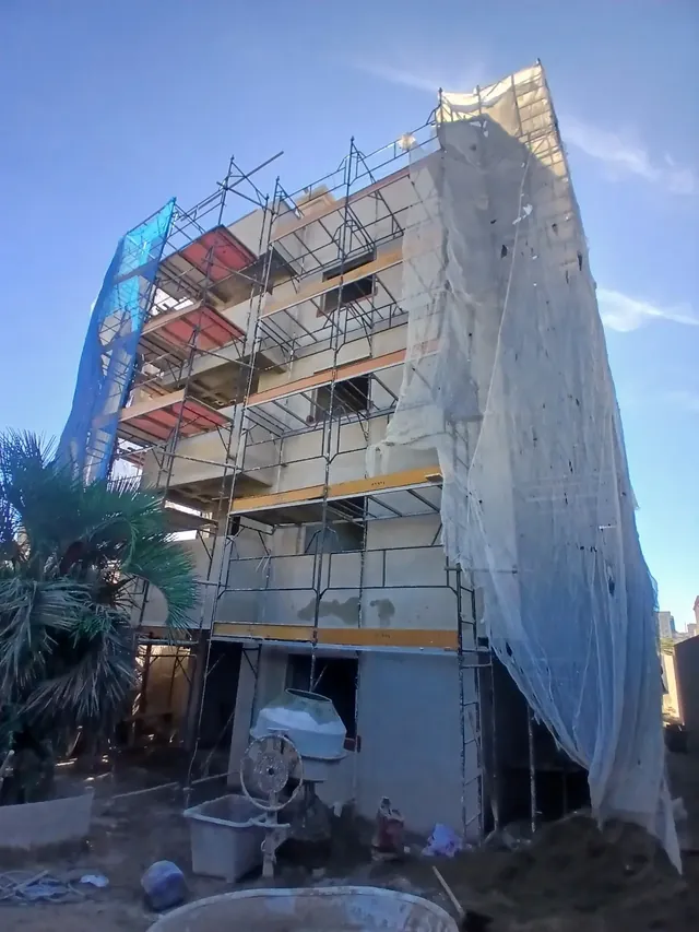 Edifício residencial em execução com estrutura e proteção de fachada